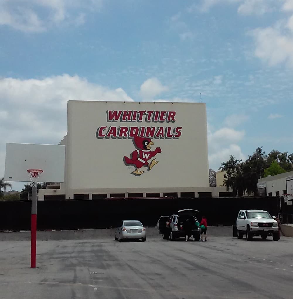 A white wall painted with the words Whittier Cardinals and a red cardinal mascot