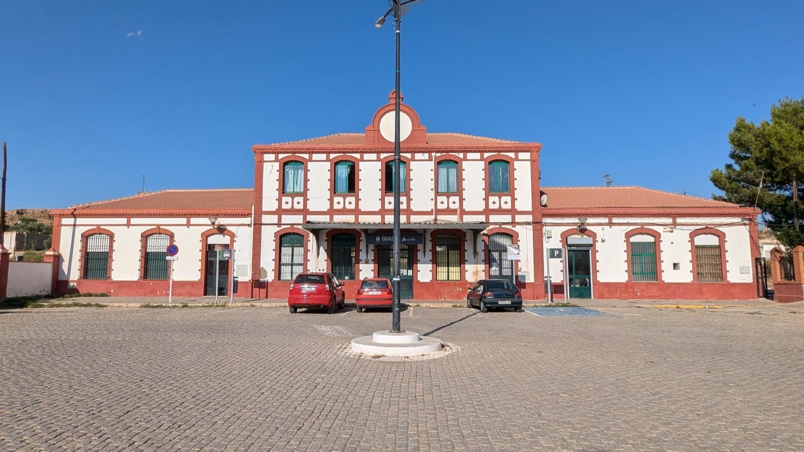 A red-and-cream station building with a clock above the entrance