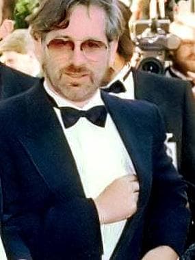 Steven Spielberg in tinted glasses and a black tie on a red carpet