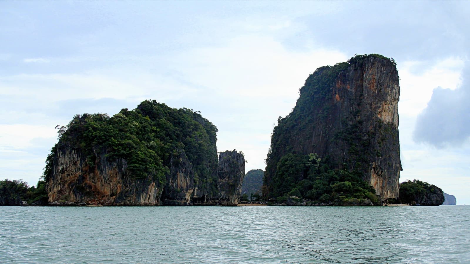 Two tall limestone islands rising sheer from calm sea
