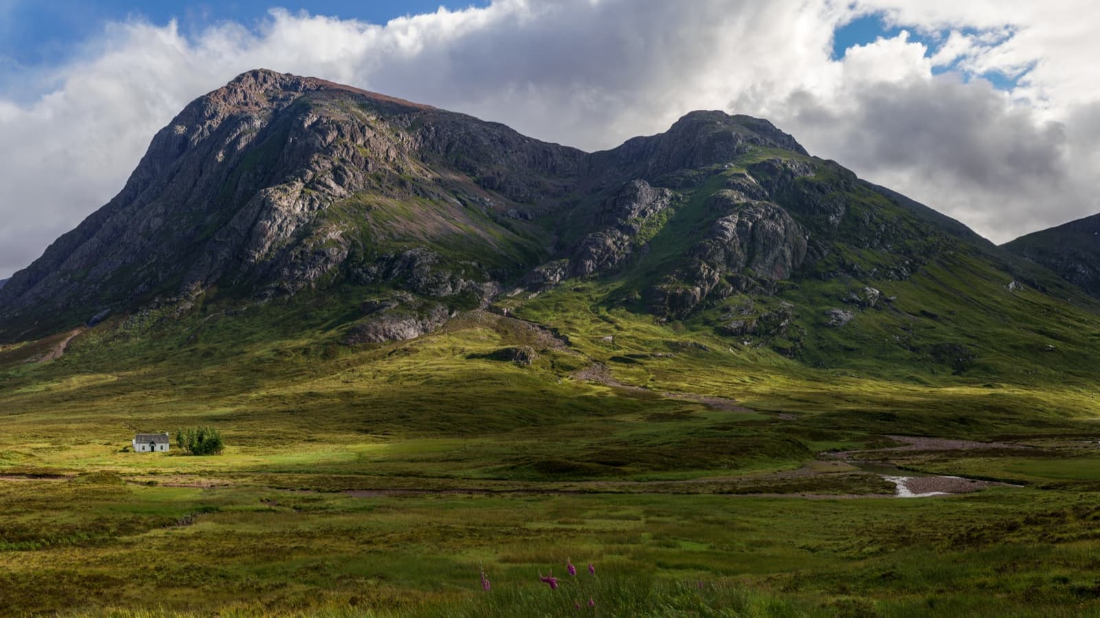 A great pyramid mountain over a green glen with a single white cottage