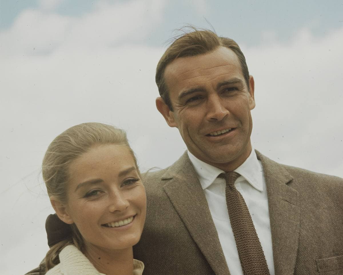 Sean Connery in a tweed jacket with his arm round a smiling Tania Mallet