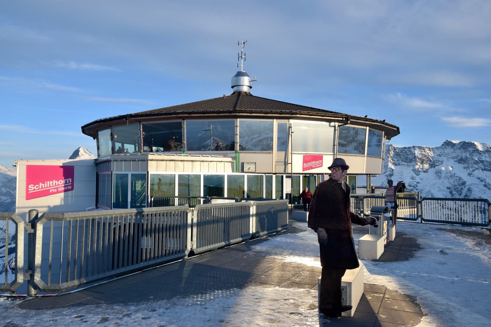 A round glass-walled restaurant on a snowy summit terrace