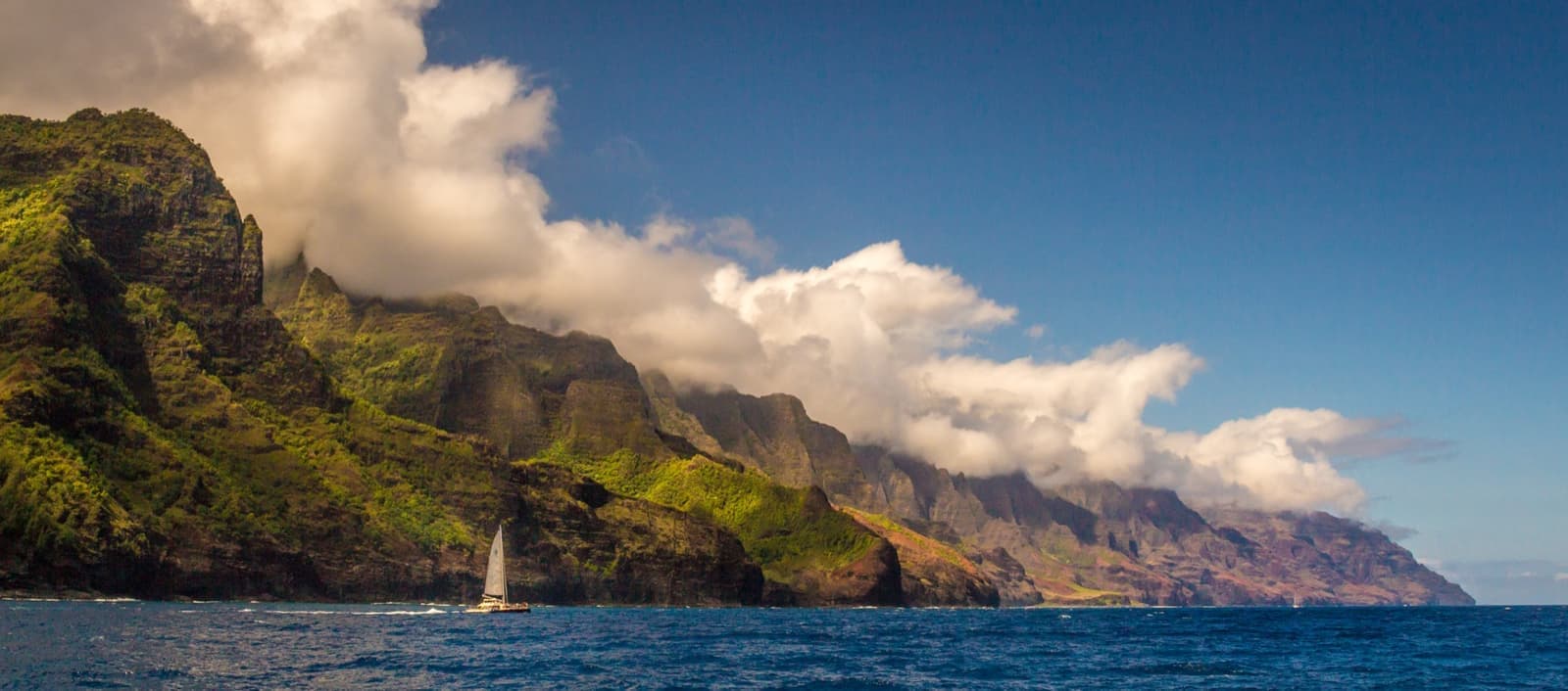 Green fluted cliffs of the Nāpali Coast above blue sea
