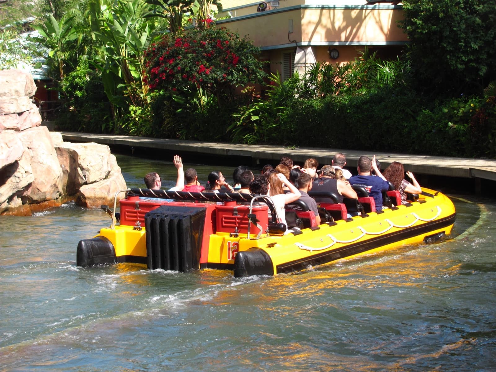 A yellow raft full of riders floating through a jungle-themed river
