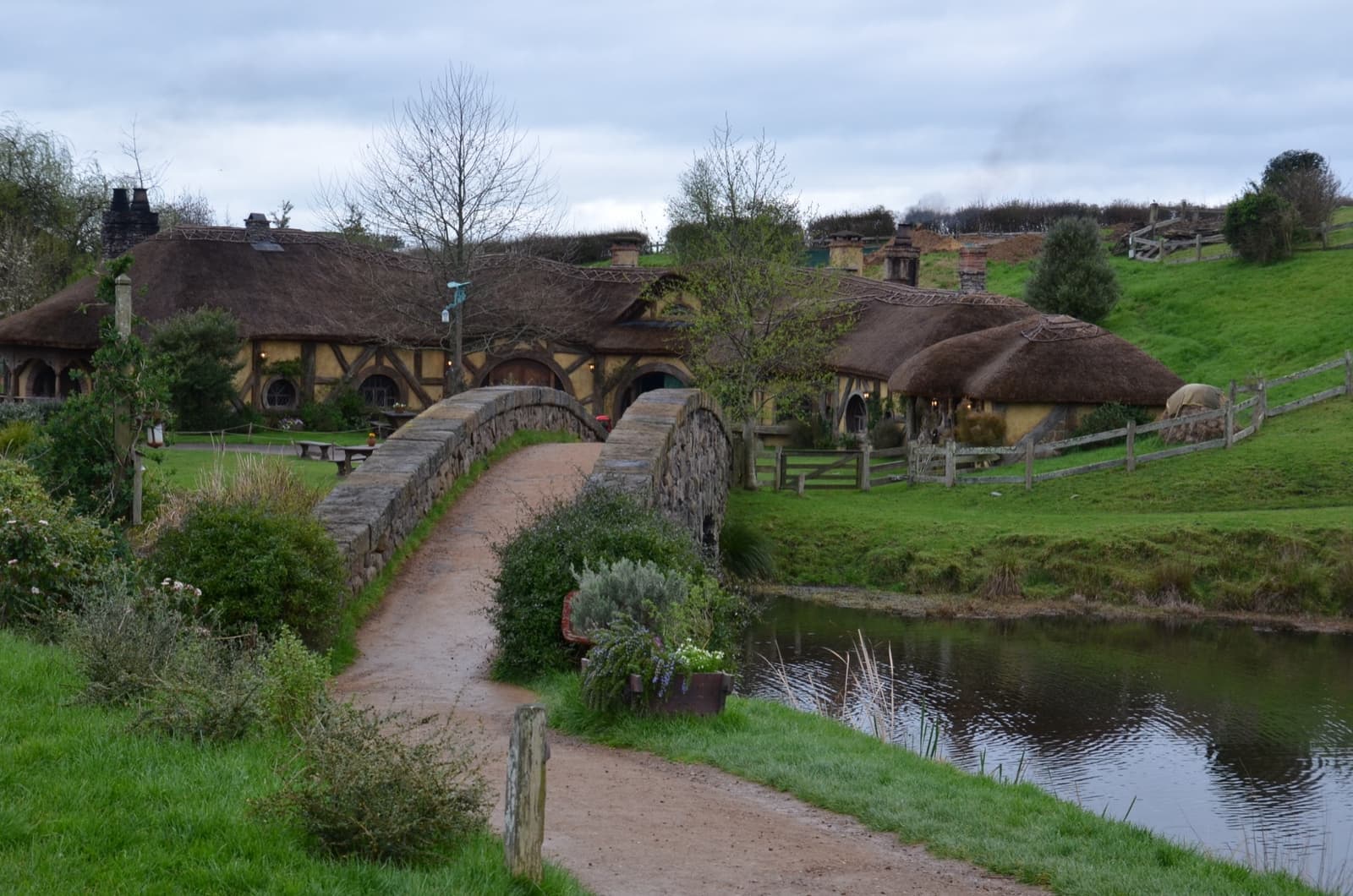 A stone arched bridge over a millpond leading to a thatched inn