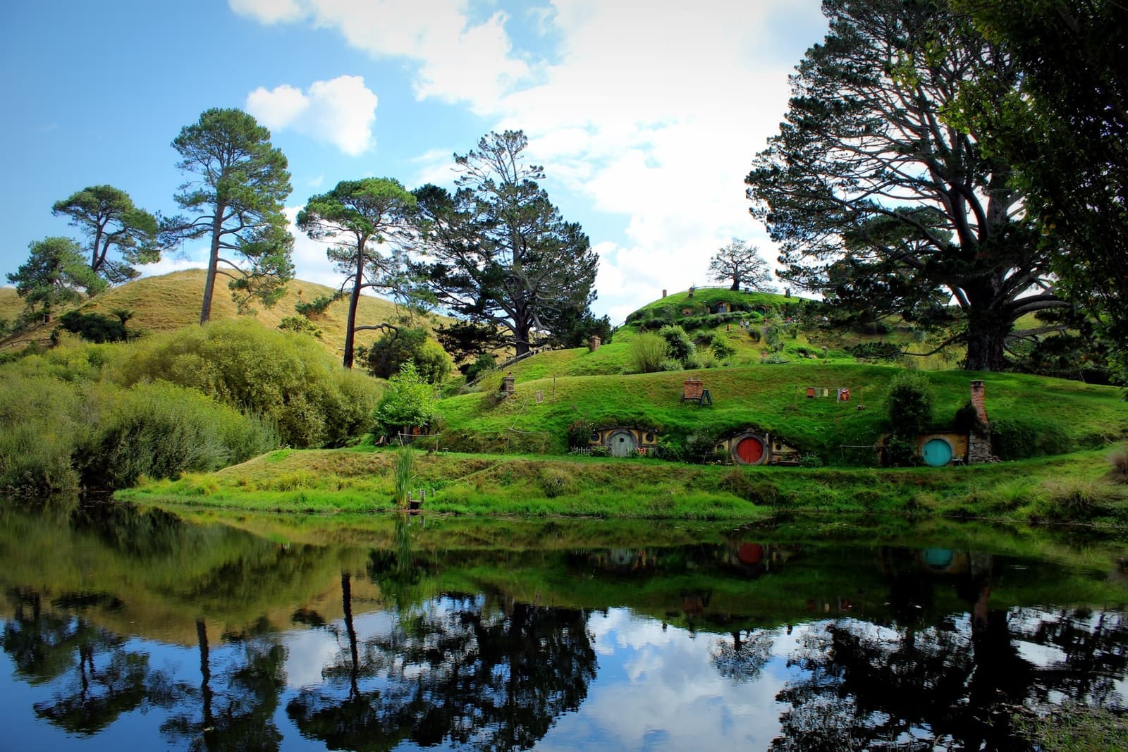 Round doors set into a grassy hillside, reflected in still water