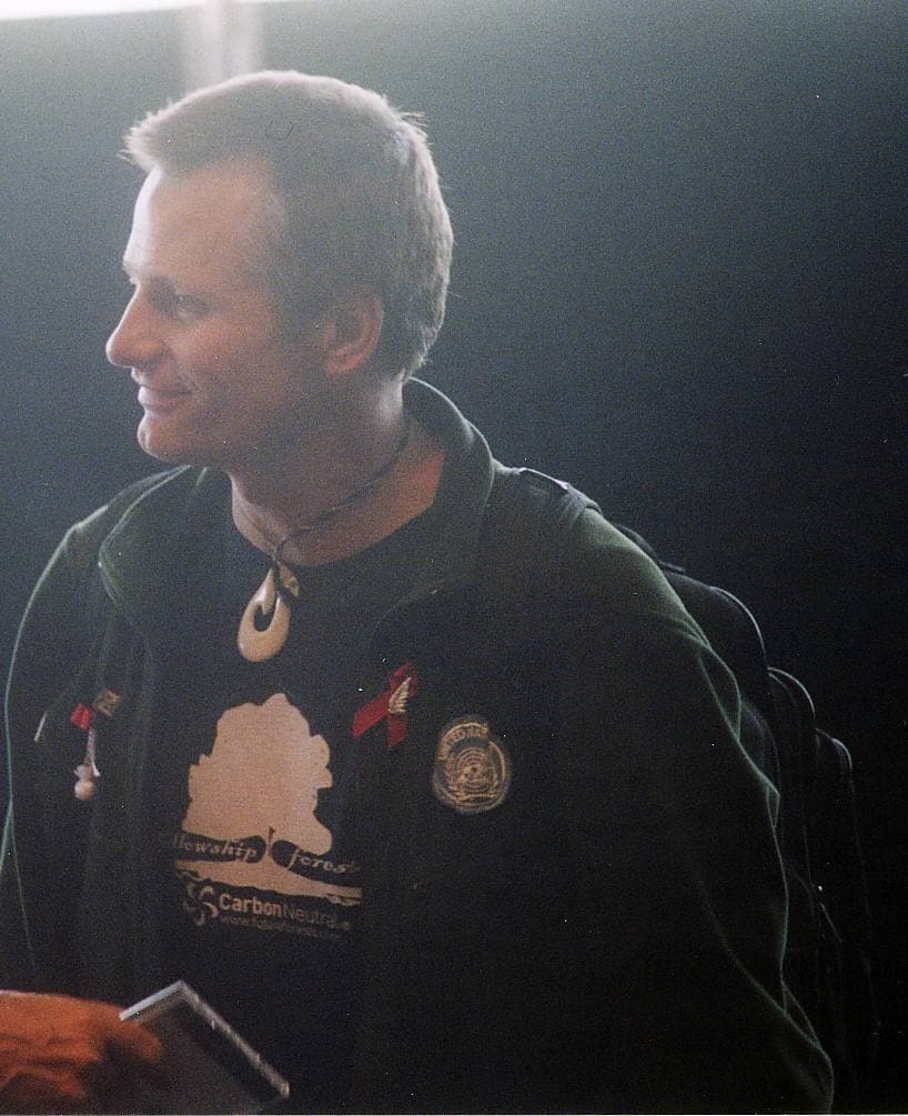 Viggo Mortensen in a green jacket and bone pendant smiles at someone