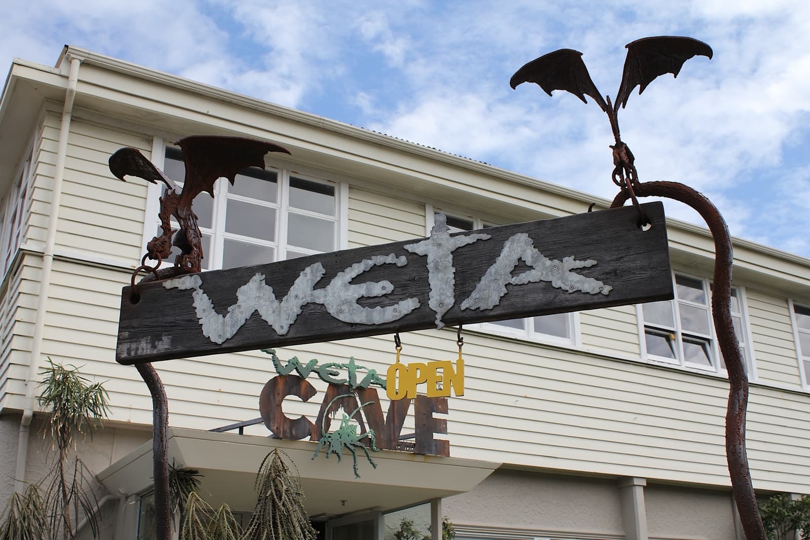 A weatherboard shopfront with its sign held by metal sculptures