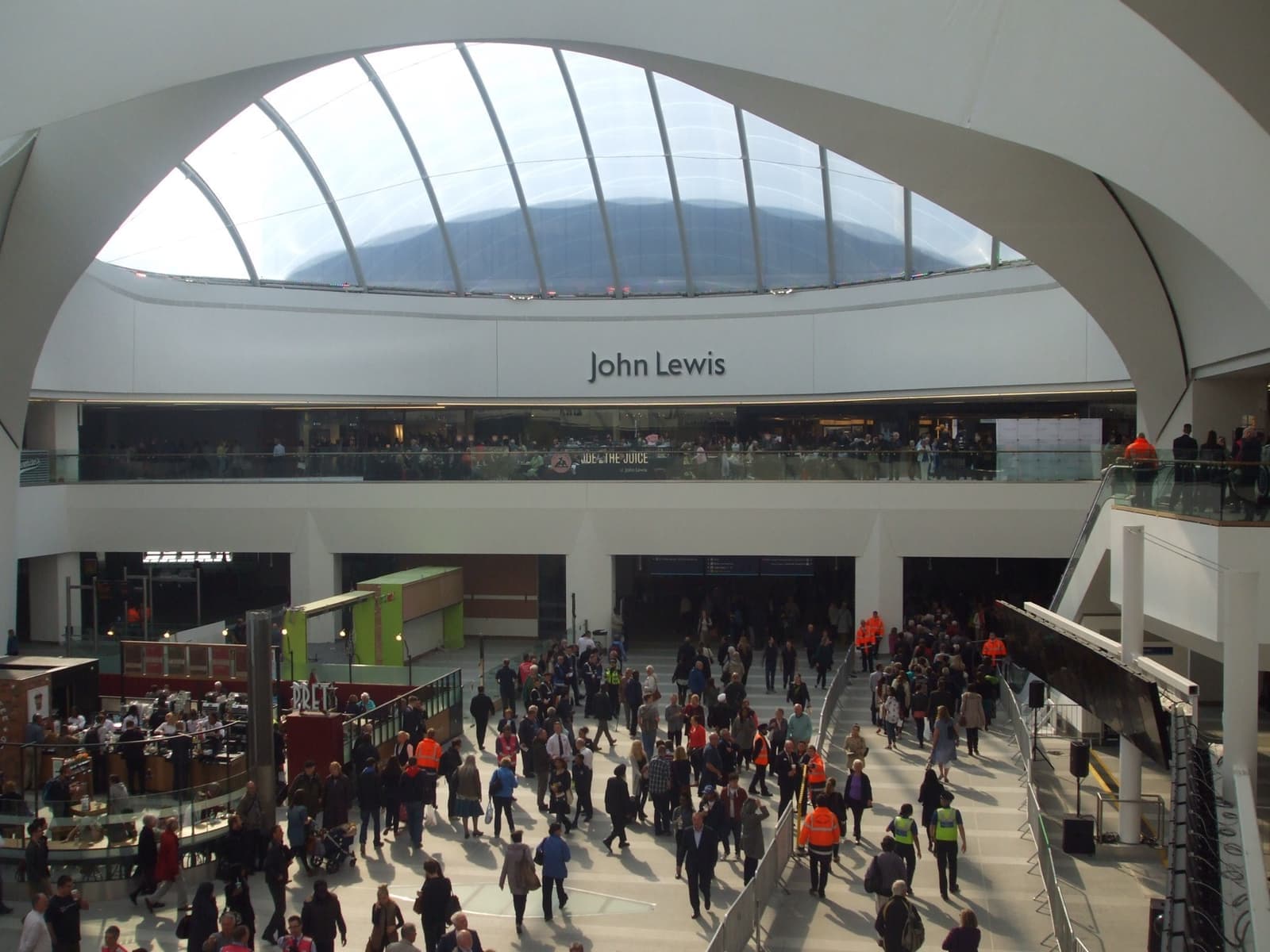 A curved mirrored building front above a station concourse
