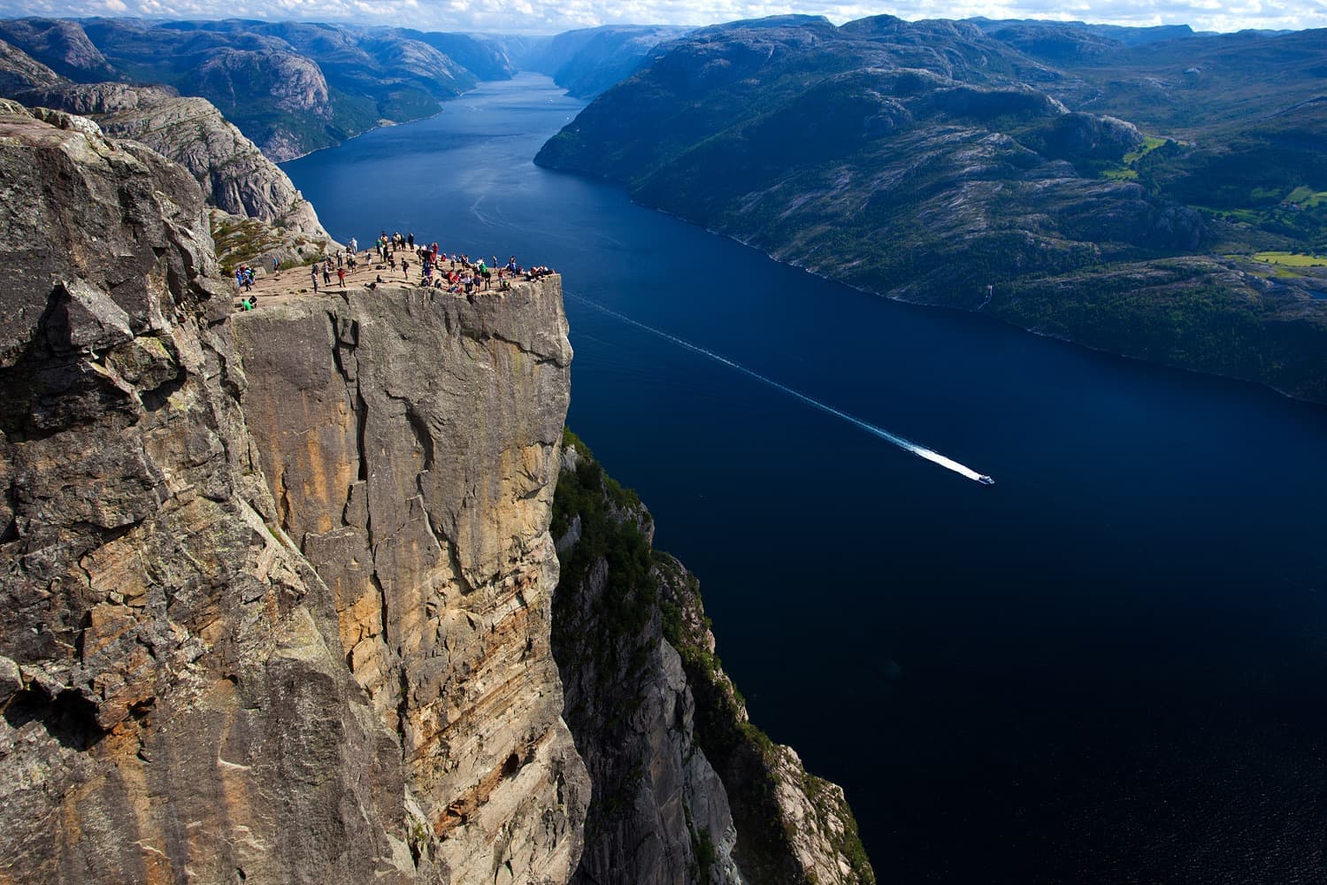 A flat-topped rock ledge hanging high over a fjord
