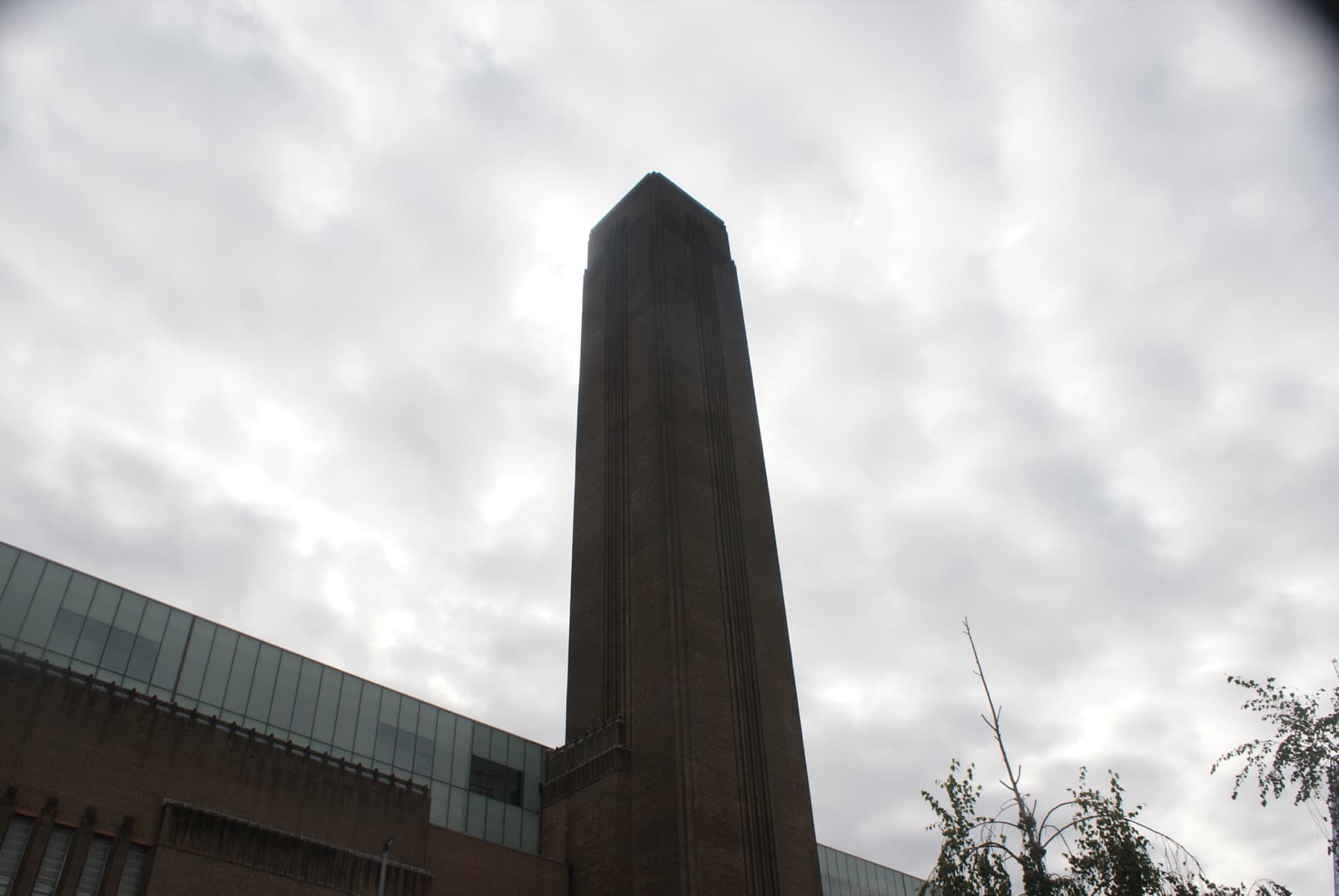 A tall square brick chimney rising above a brick building