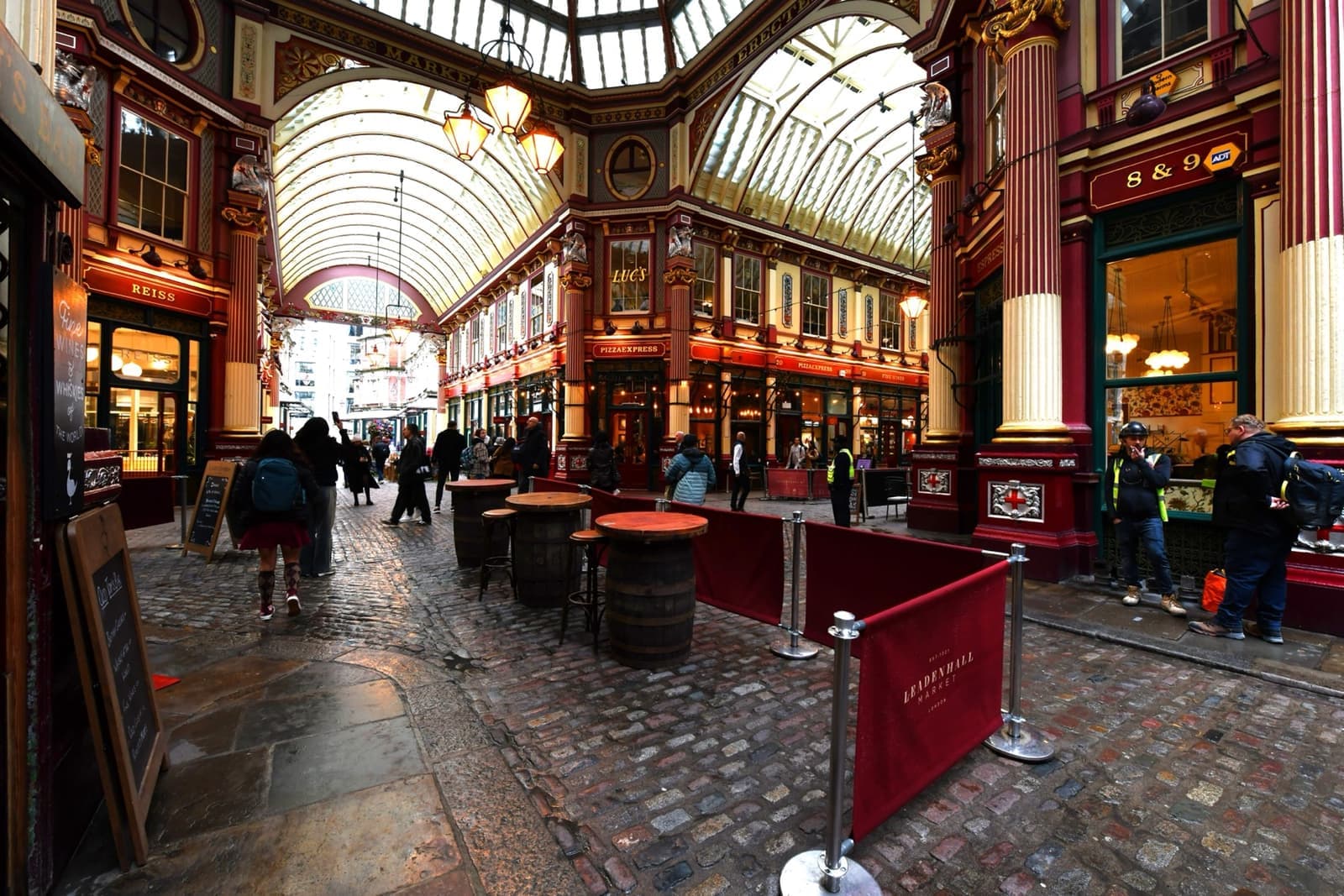 A cobbled arcade of shopfronts under a glazed roof