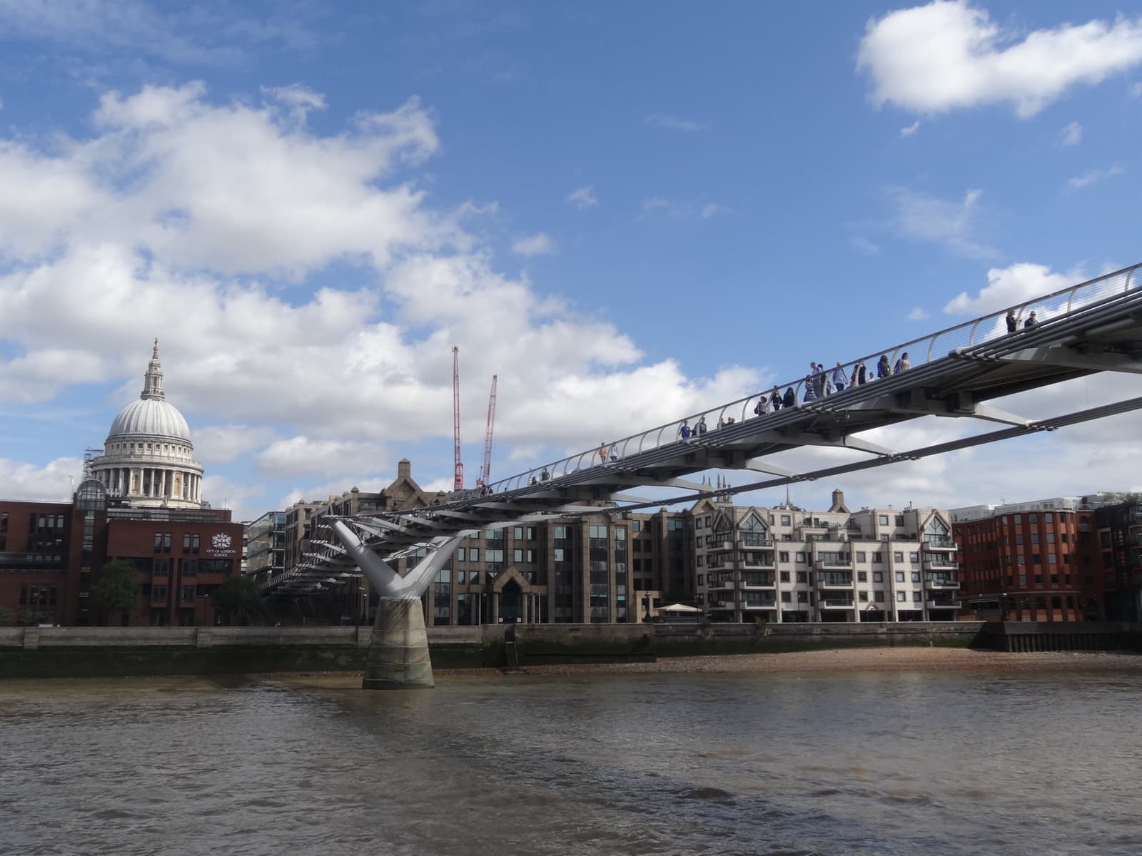 A low steel footbridge across the Thames with the dome of St Paul’s behind