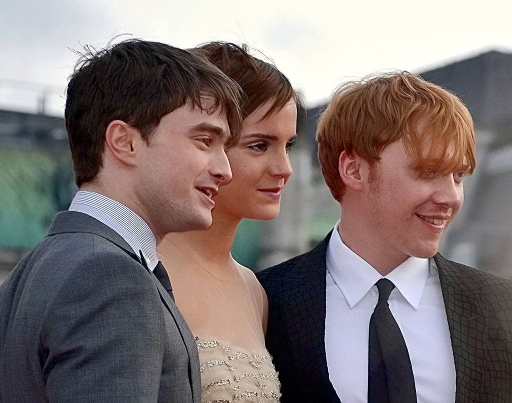 The three young leads side by side, smiling, outdoors