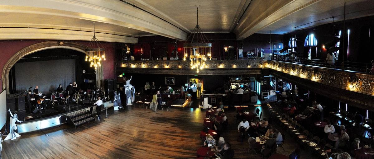 A wide ballroom with a wooden floor, balcony and stage