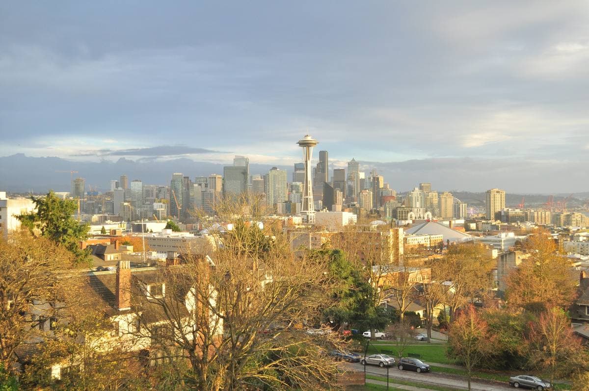 People at a railing in front of the Space Needle and downtown towers