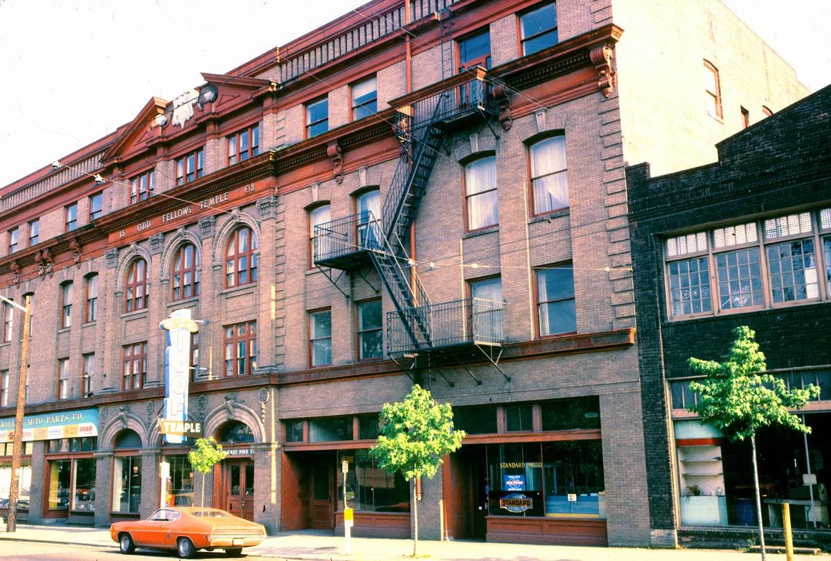 A red-brick five-storey hall with fire escapes on a street corner