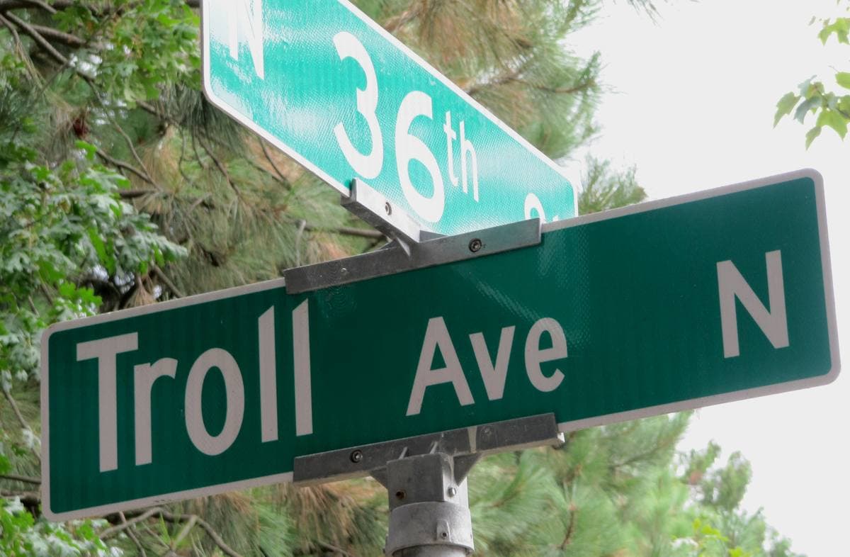 Green street sign reading Troll Ave N
