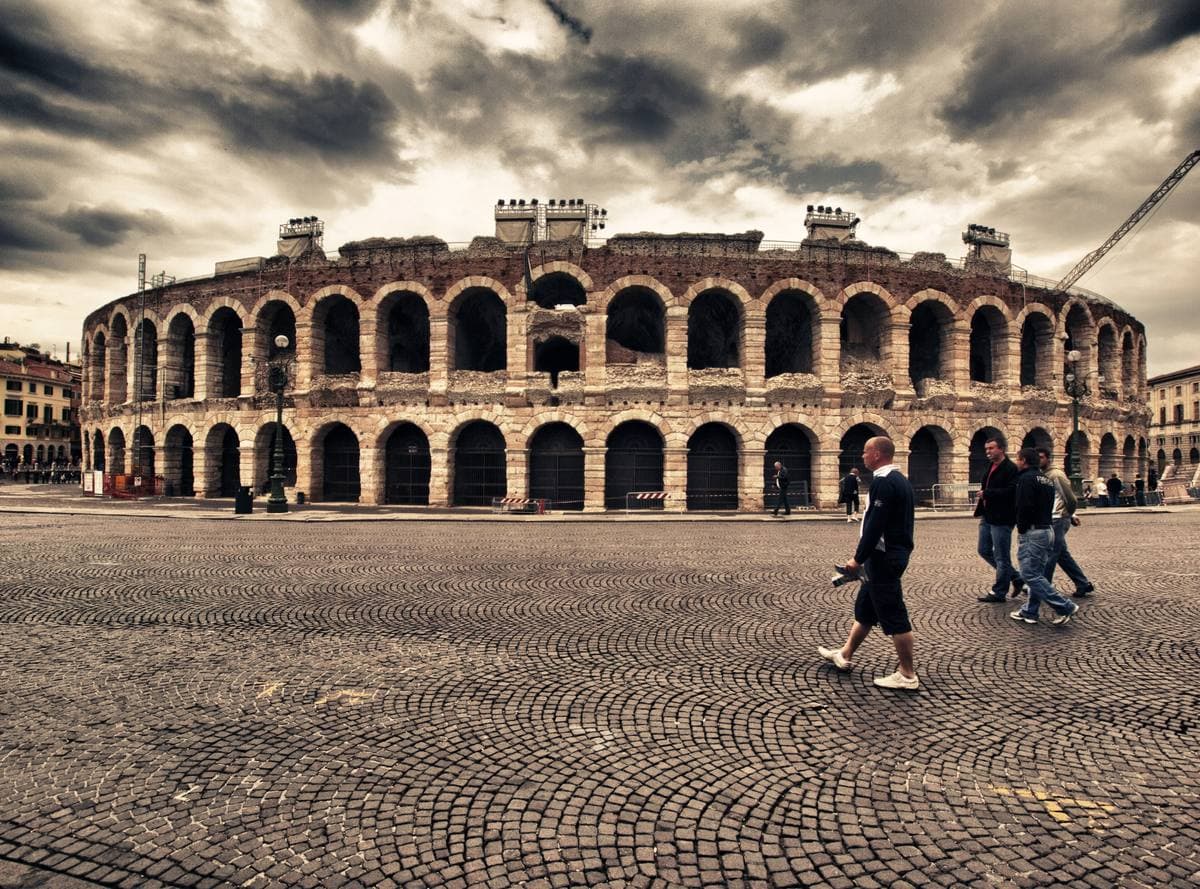 The arcaded stone arena of Verona under a cloudy sky