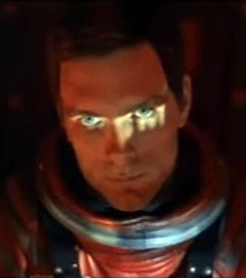 Keir Dullea in a red spacesuit helmet, lit from below, staring upward