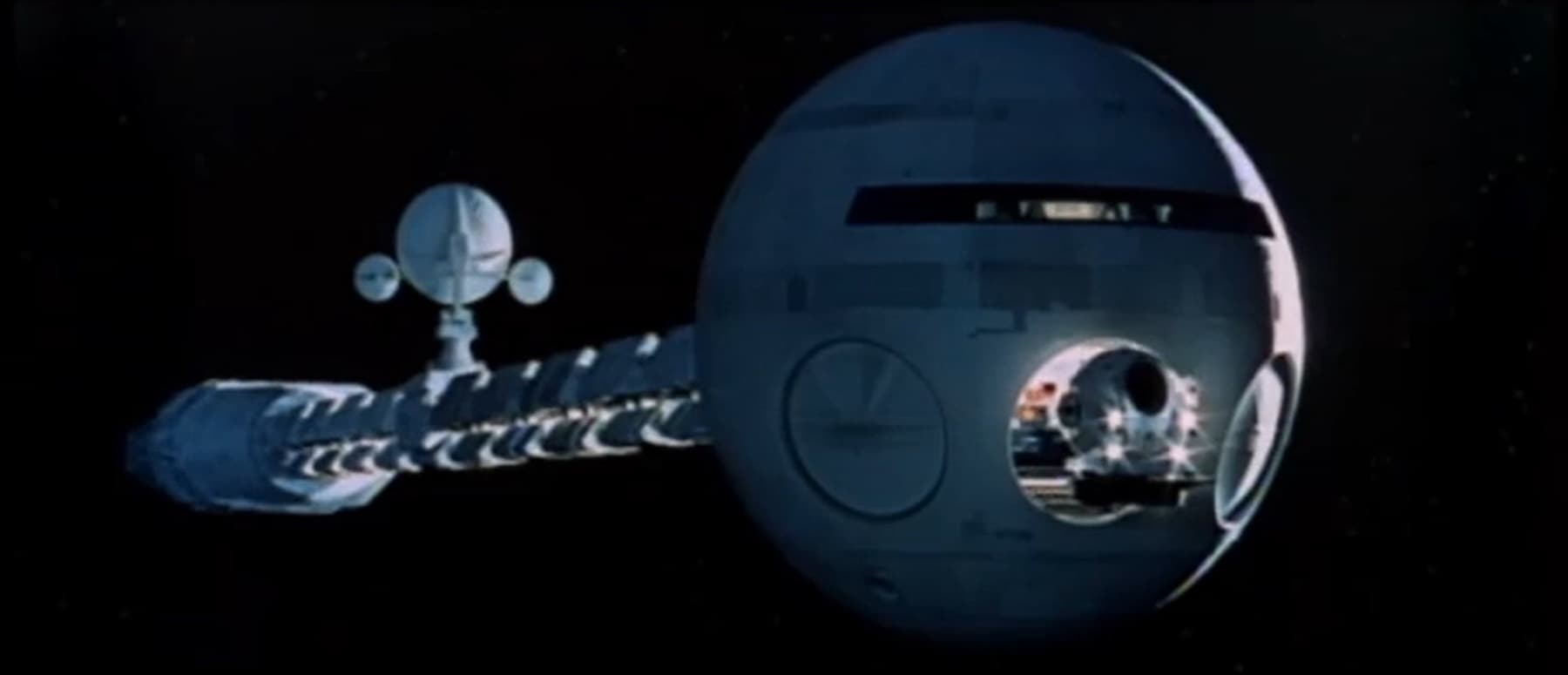 A long white spaceship with a spherical head in black space, a small pod beside it