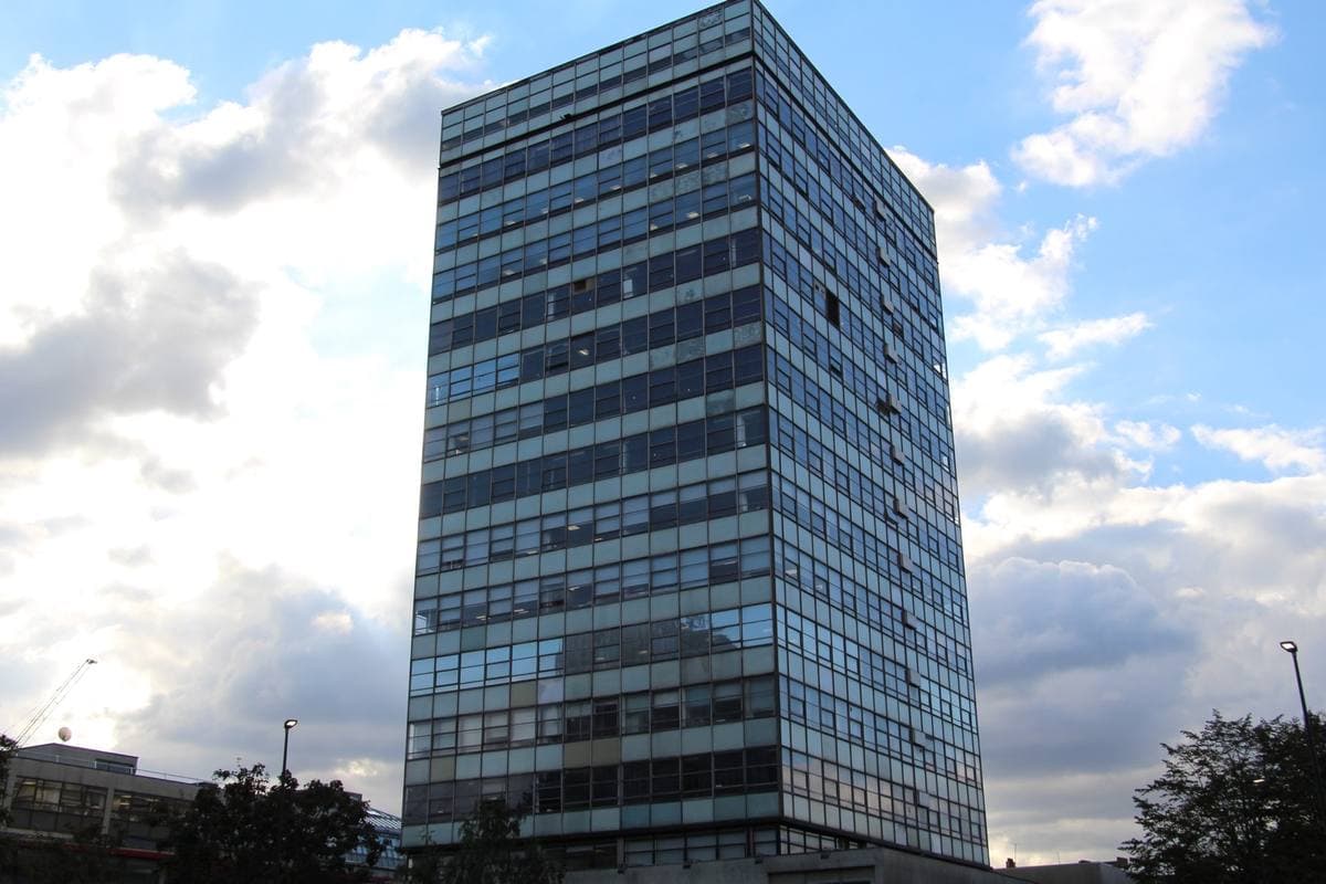 A tall glass tower block against a cloudy sky