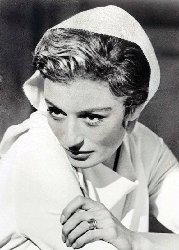Anouk Aimée in a white headscarf, hands folded under her chin