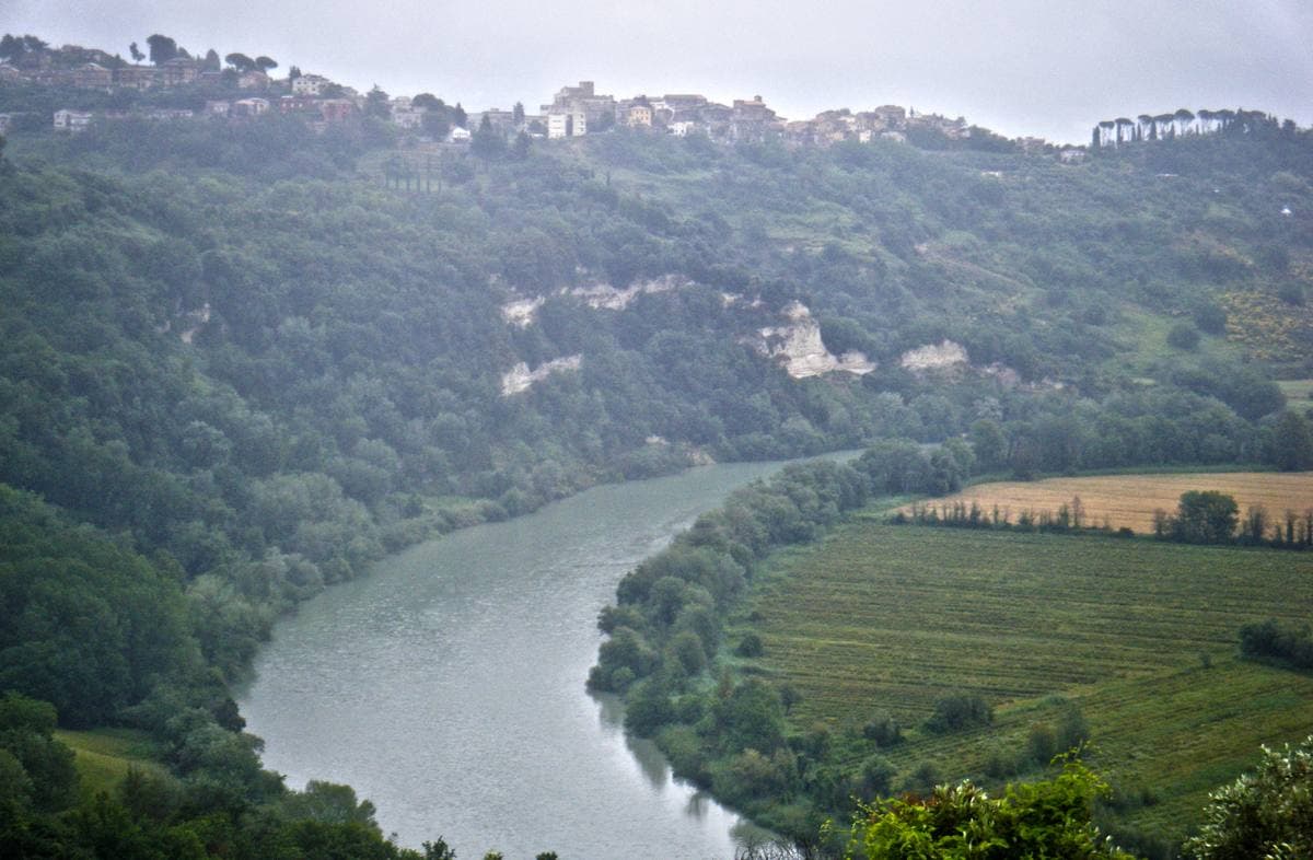 A green river valley with a village on the ridge above it