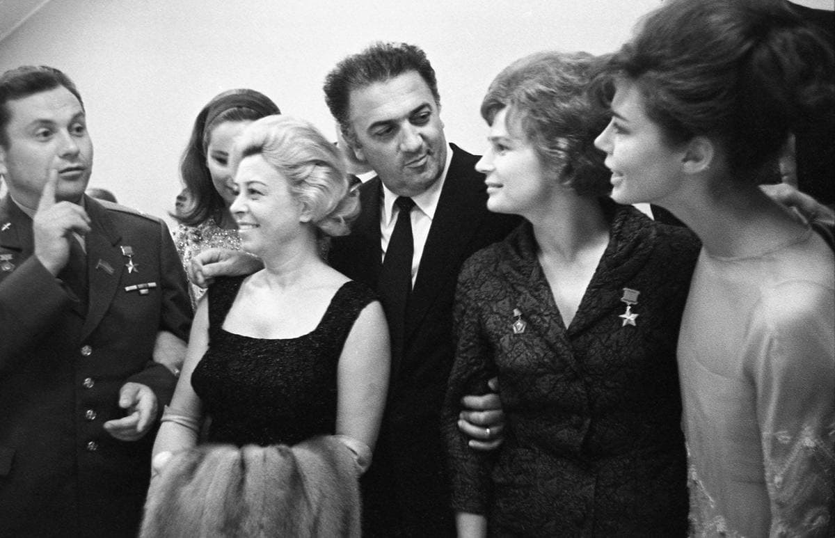 Fellini in a dark suit among a crowd with Giulietta Masina and two Soviet cosmonauts