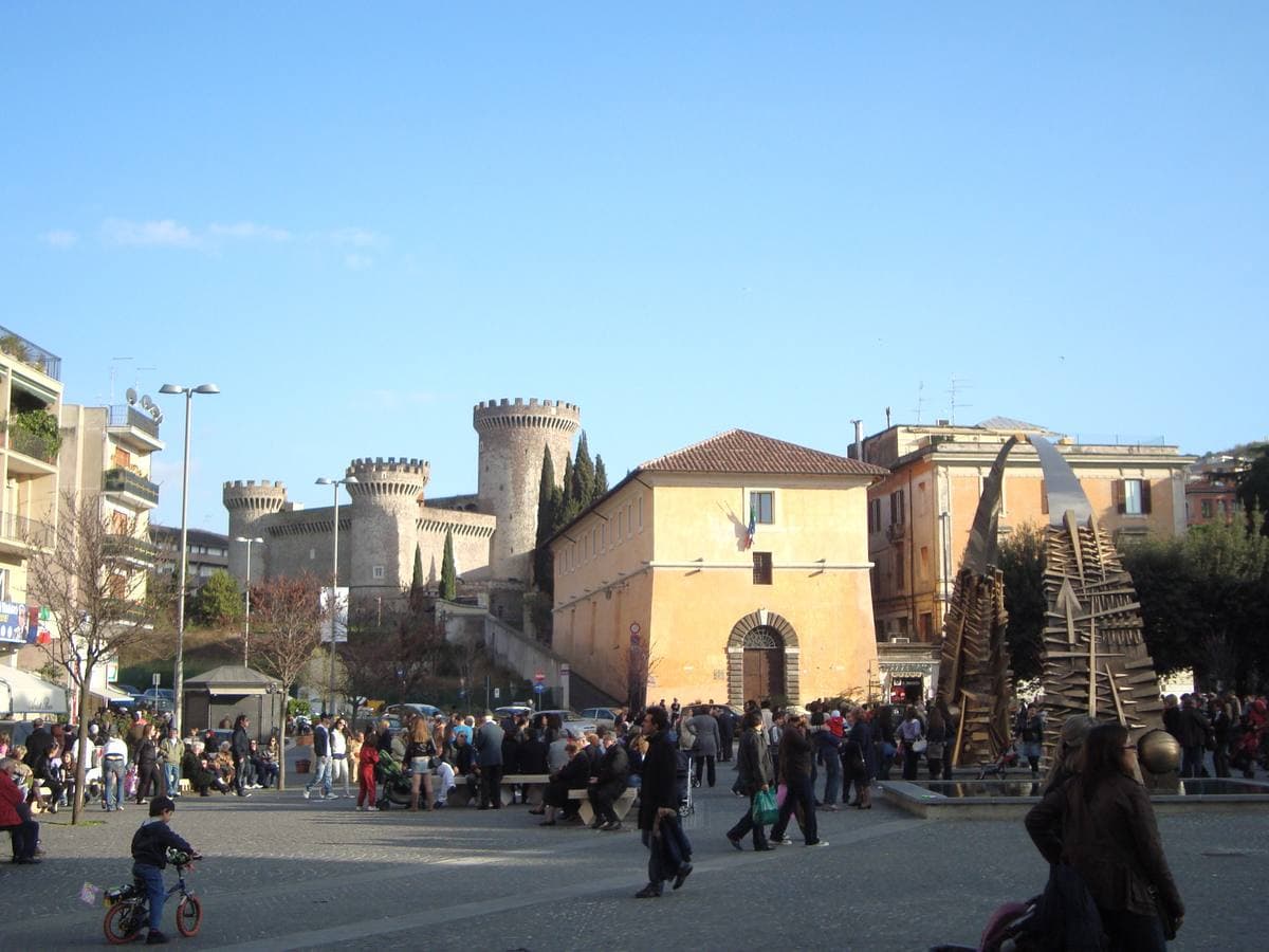 A busy town square with a round-towered castle behind it