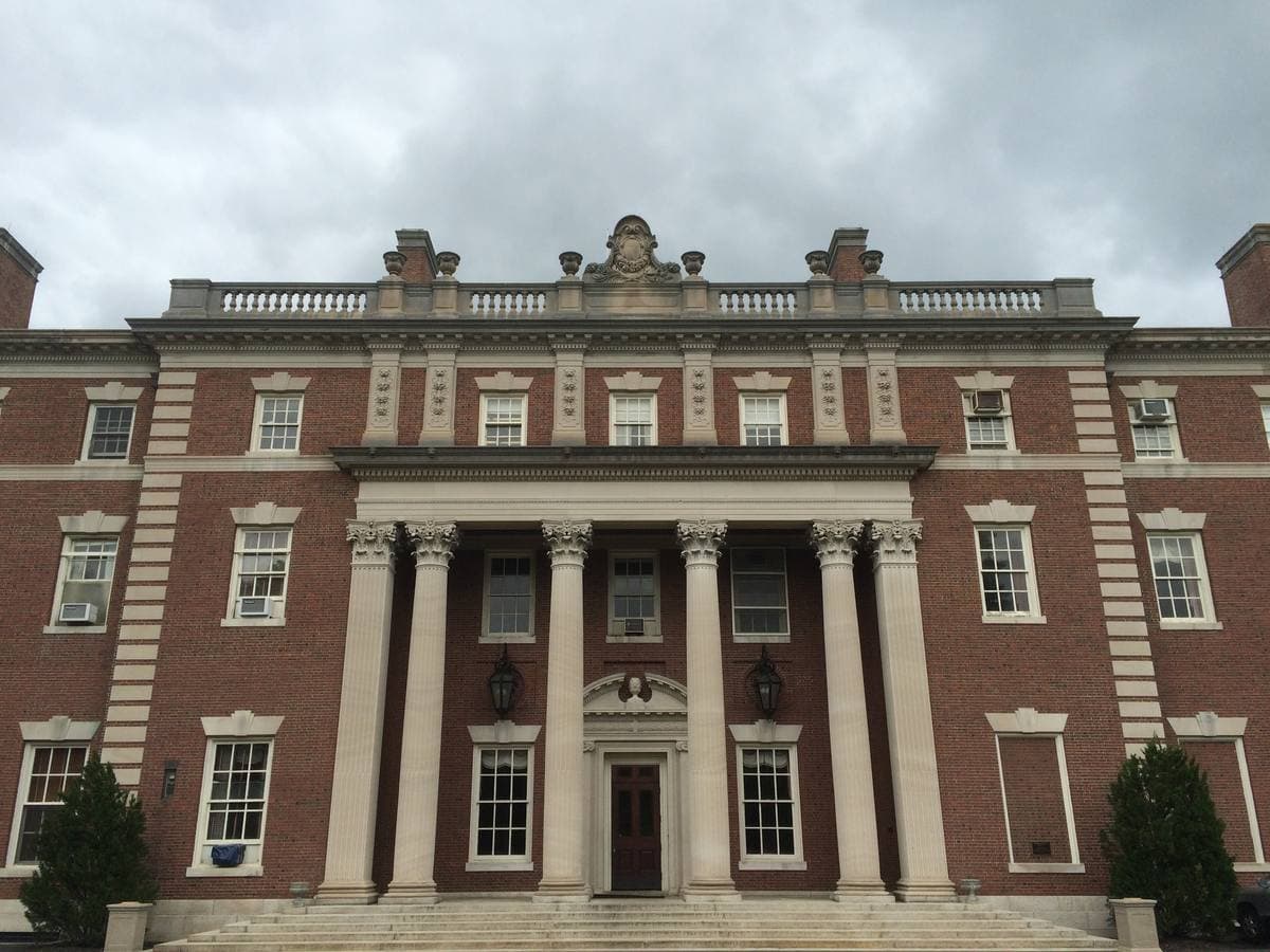 A red-brick Georgian Revival mansion with a columned stone portico under a grey sky