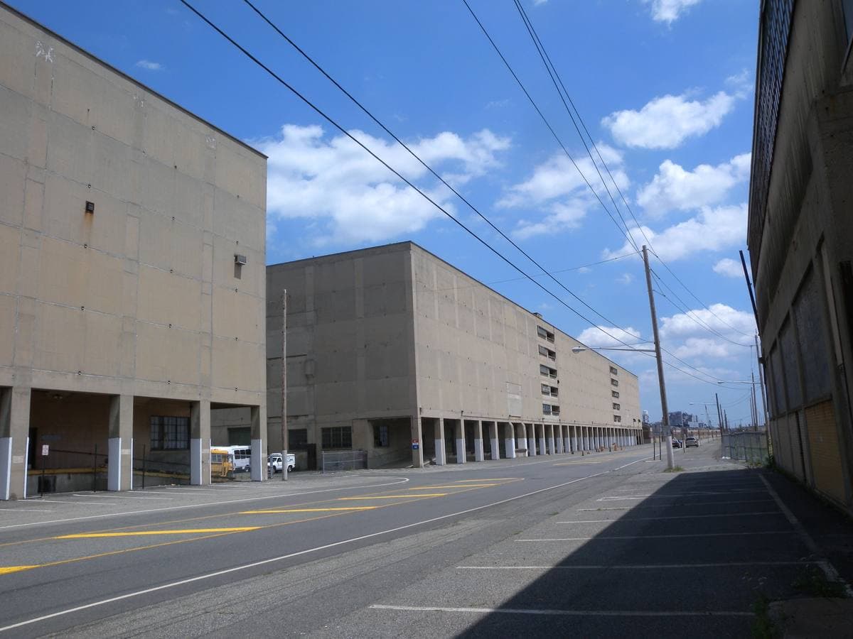 Long concrete warehouse blocks along an empty road under a blue sky
