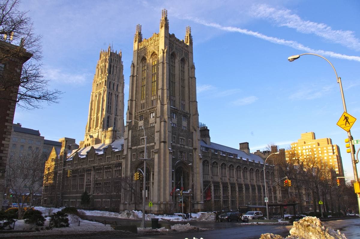 Gothic towers of a seminary in golden light, a snowy street corner in front