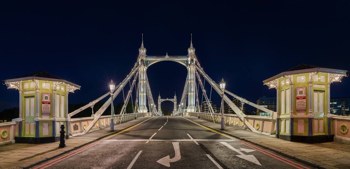 A suspension bridge outlined in thousands of small lights over the dark Thames