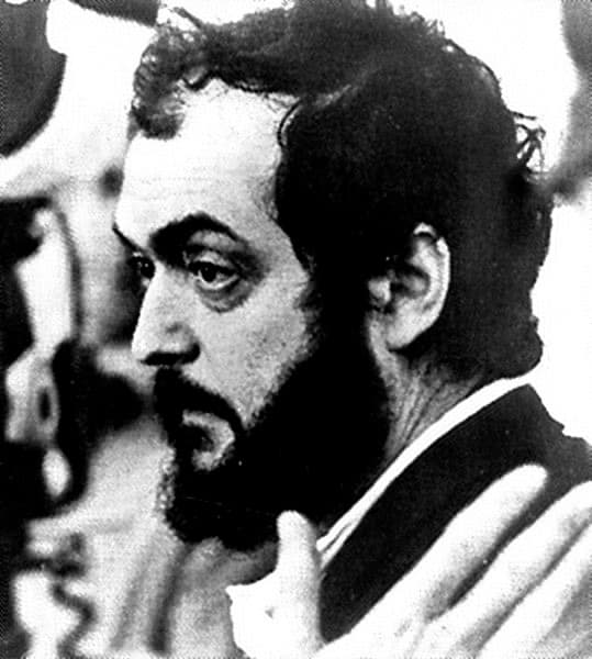 Stanley Kubrick in profile, bearded, beside a film camera