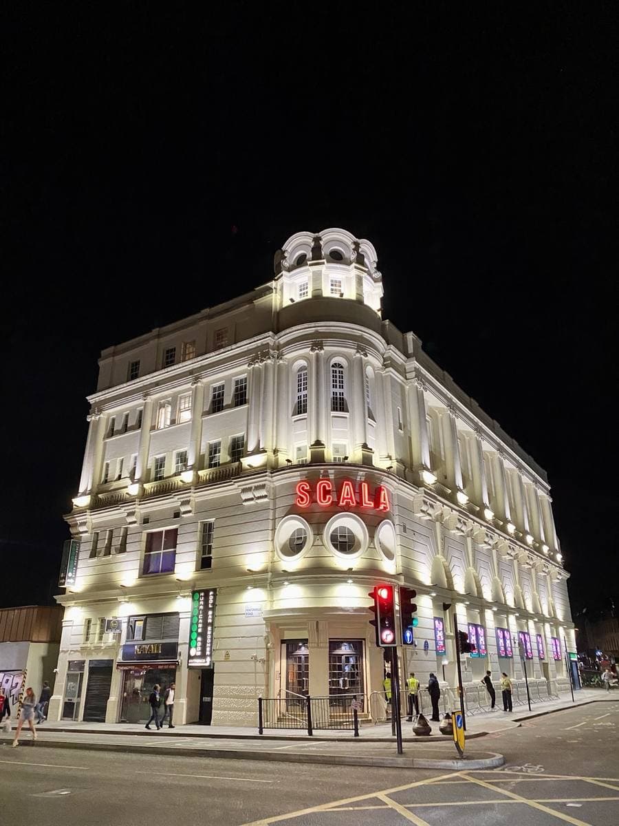 A floodlit cream corner building with SCALA in red letters