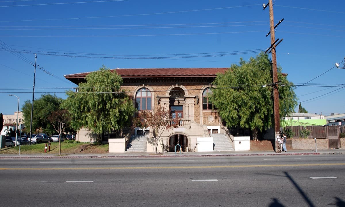 A brick and stone two-storey library with arched windows and a front lawn