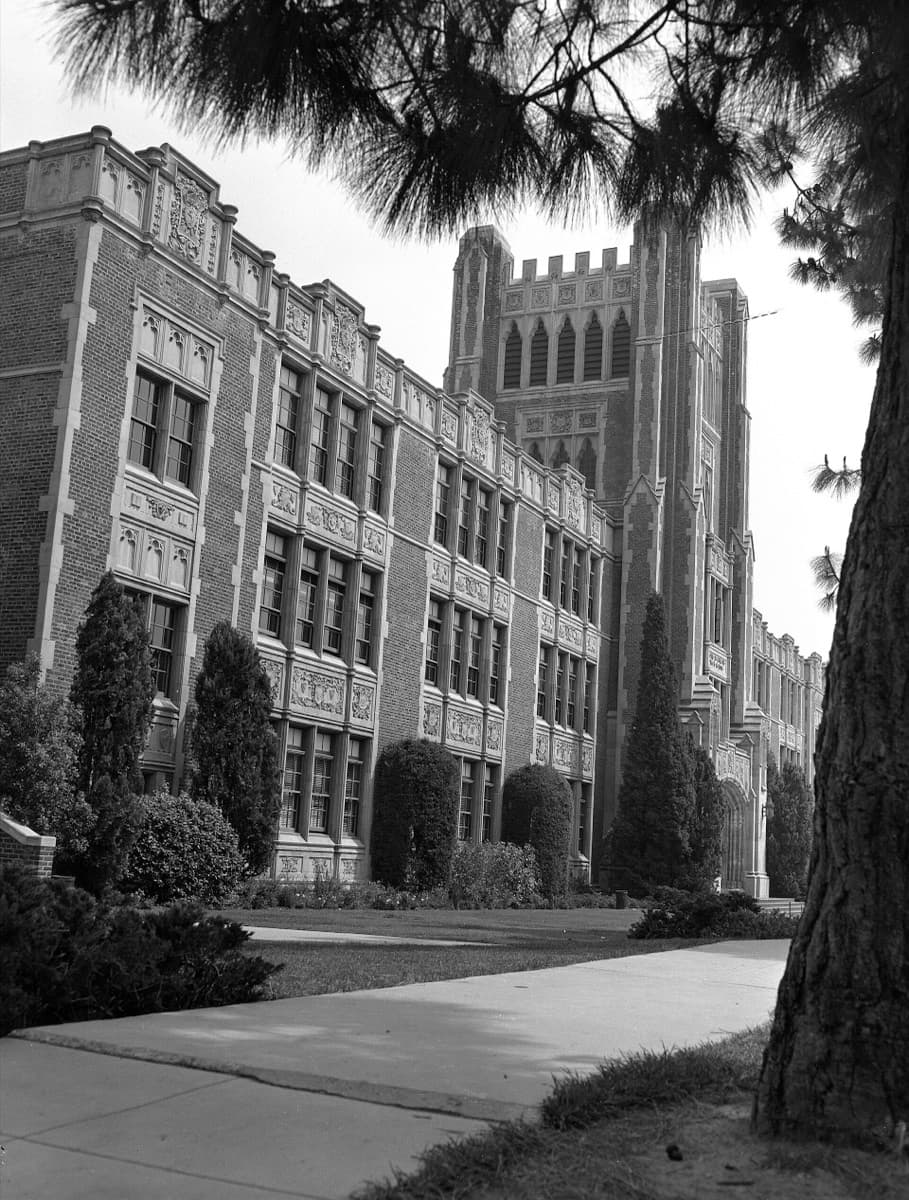 A black-and-white view of a Collegiate Gothic school building with a tower and steps