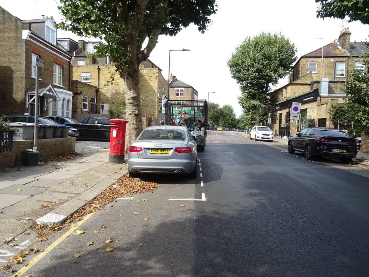 A quiet residential road with parked cars and plane trees