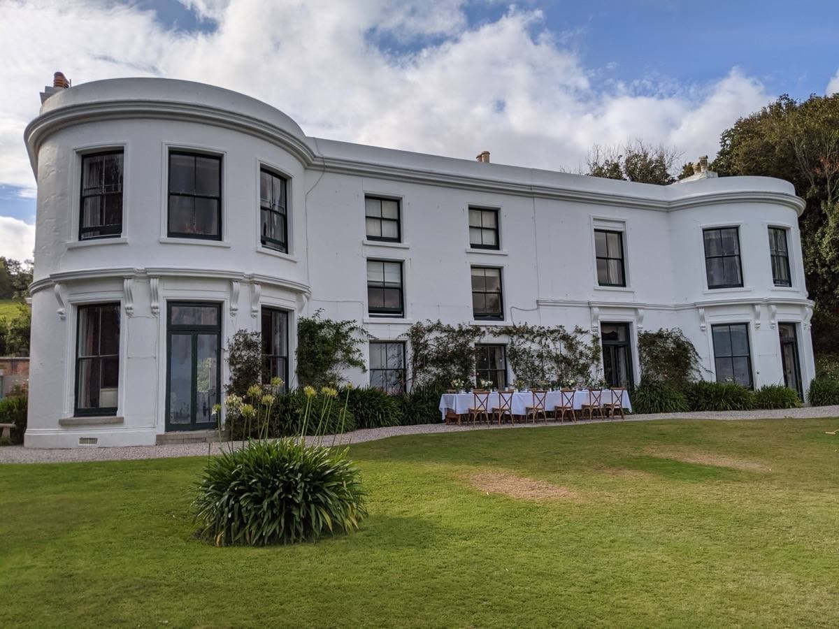A long white stucco house with curved bay ends on a lawn