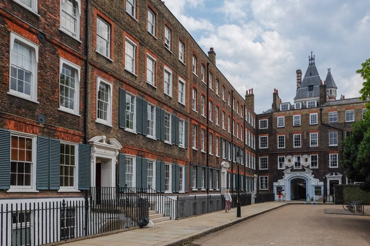A square of tall red-brick seventeenth-century chambers round a paved court