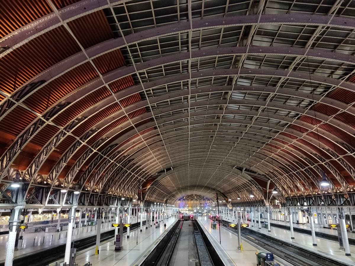 The long arched iron and glass roof of Paddington station over empty platforms