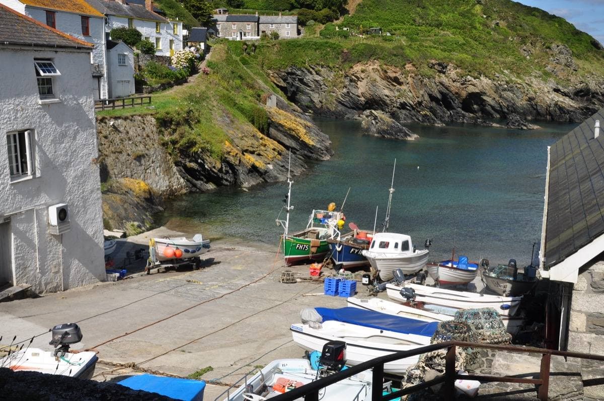 Small boats drawn up on a slipway in a rocky green cove