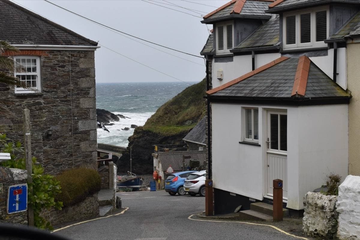 A narrow lane between slate houses dropping to a rocky cove