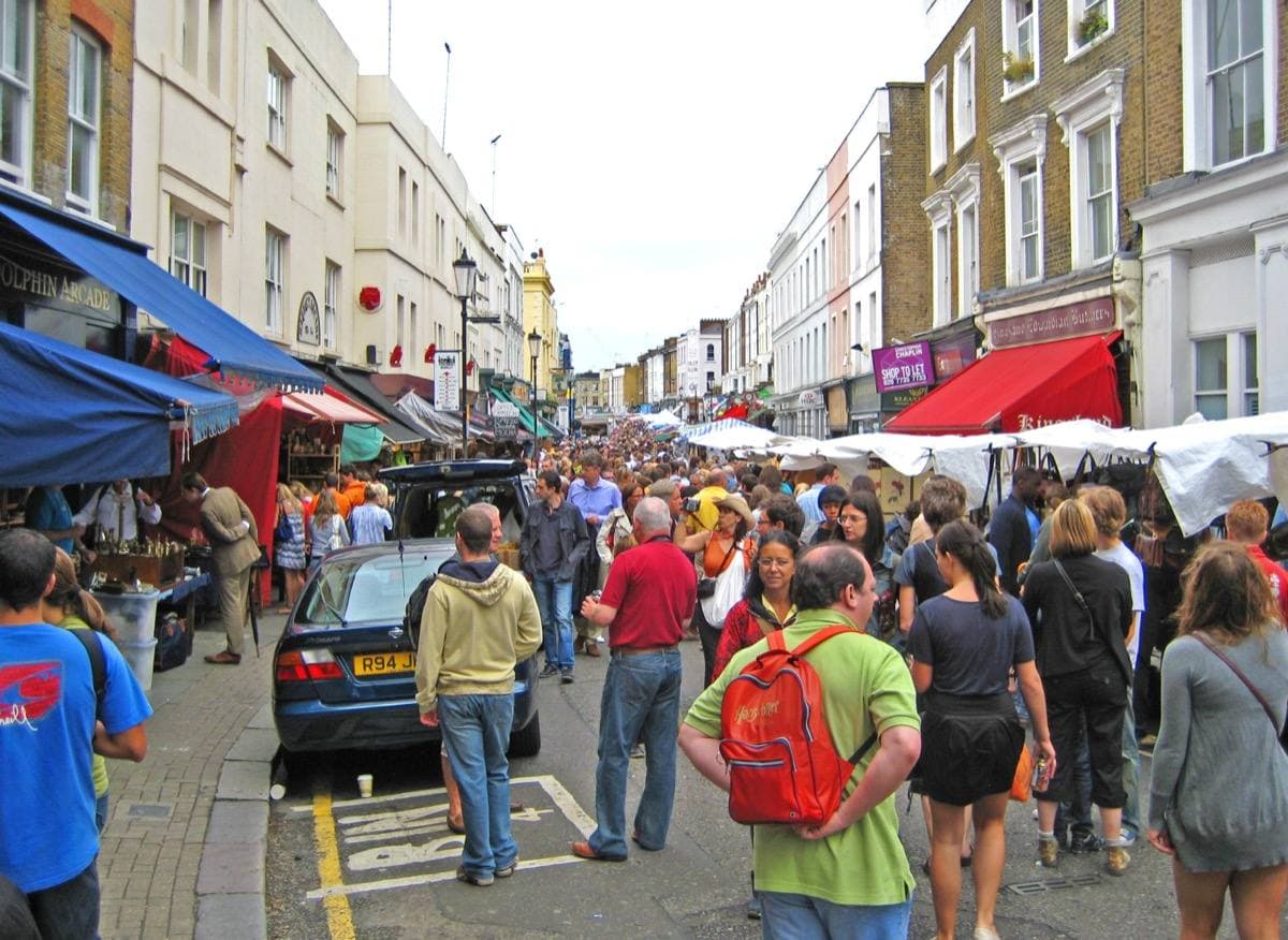 A crowded market street with stalls and painted terraces