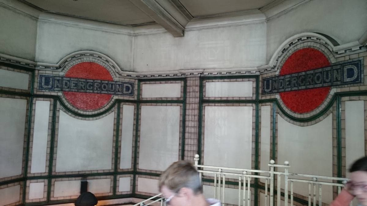 Two red-and-white mosaic Underground roundels on a tiled wall