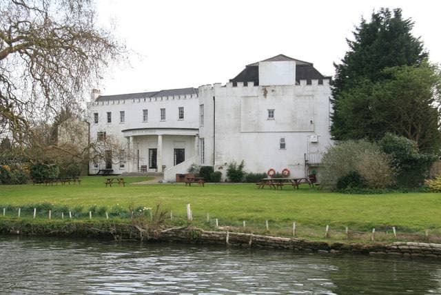 A white Georgian house with a lawn running down to the river