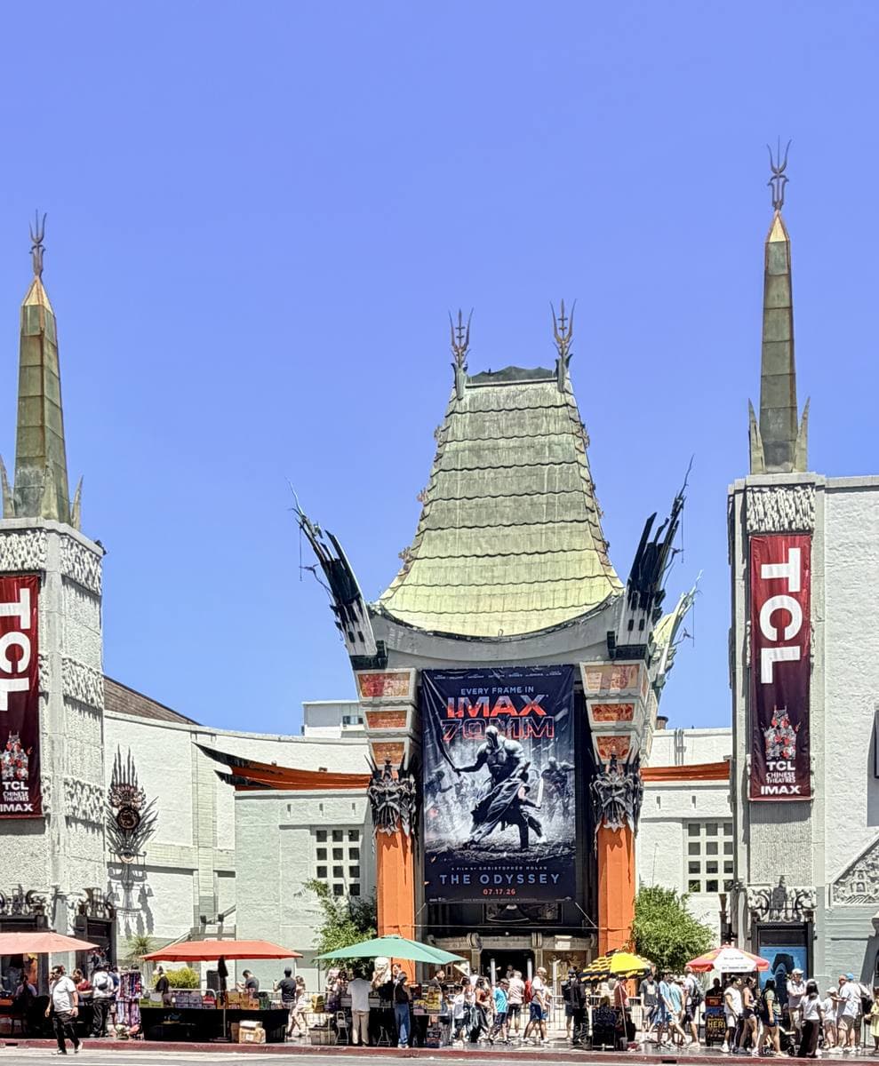 The green pagoda roof of the Chinese Theatre with red columns and a crowd in the forecourt