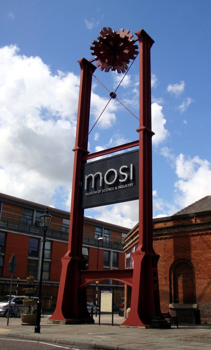 A tall red steel gateway with a spiked wheel at the top and a MOSI sign